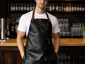 Bartender wearing Chaser real cowhide leather bar apron in black with dual gold zip bib pockets, brown leather neck straps, brass rivets and lower front pockets in a bar
